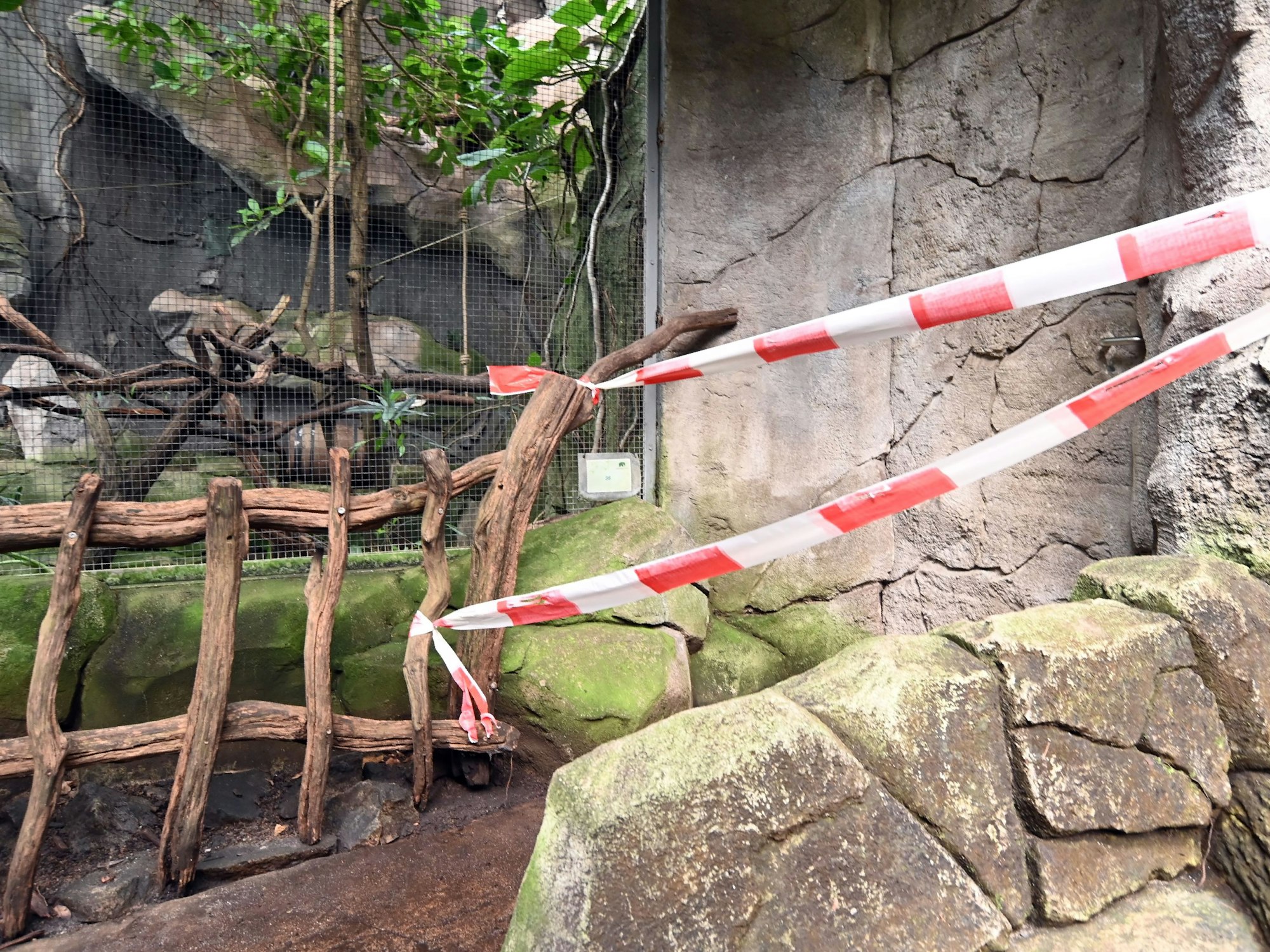 Ein Flatterband hängt an einer Absperrung in einem Zoo.