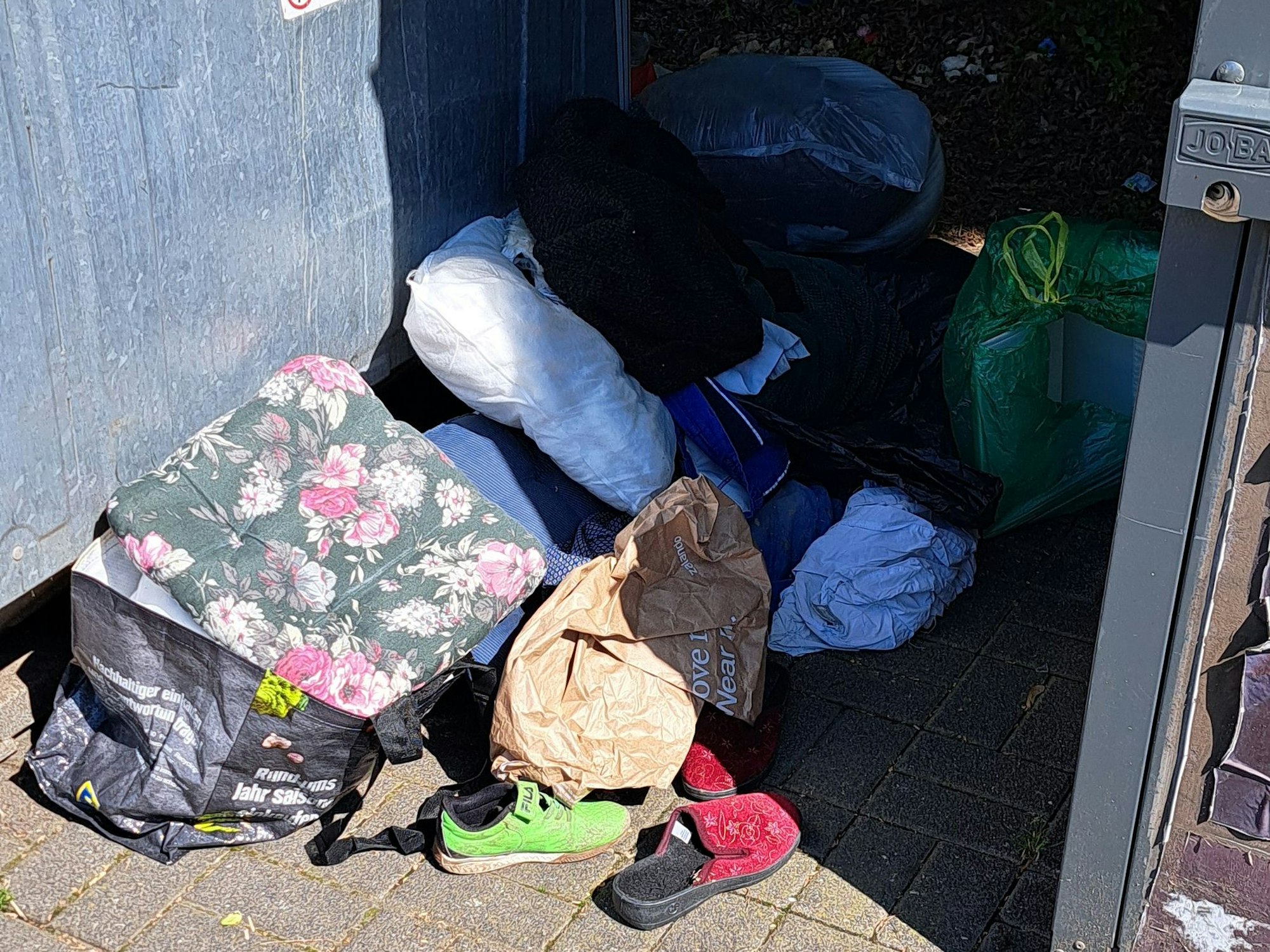 Müll liegt neben den Containern in Köln-Zündorf in der Houdainer Straße.