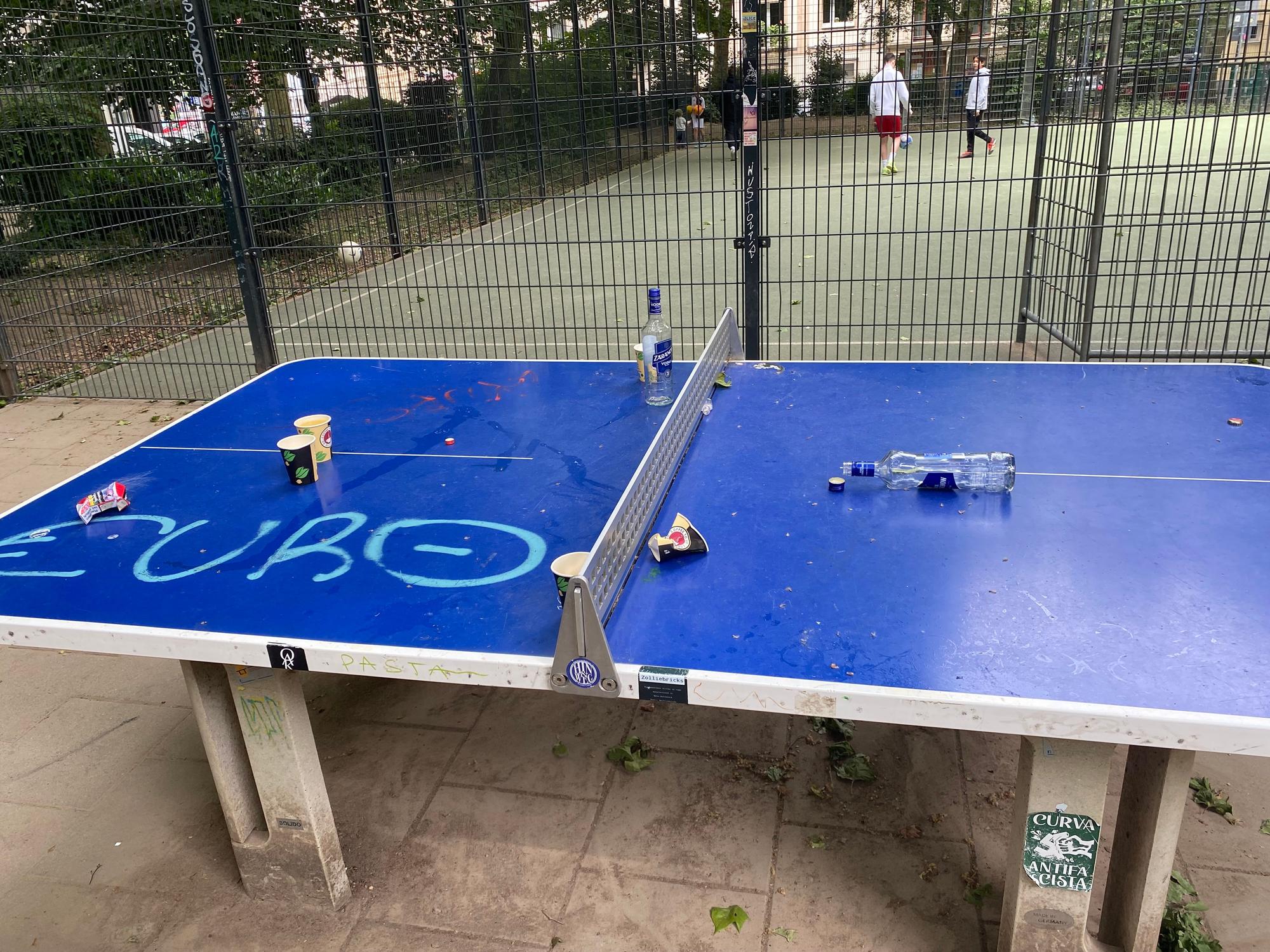 Leere Flaschen und Becher liegen auf einer Tischtennisplatte.