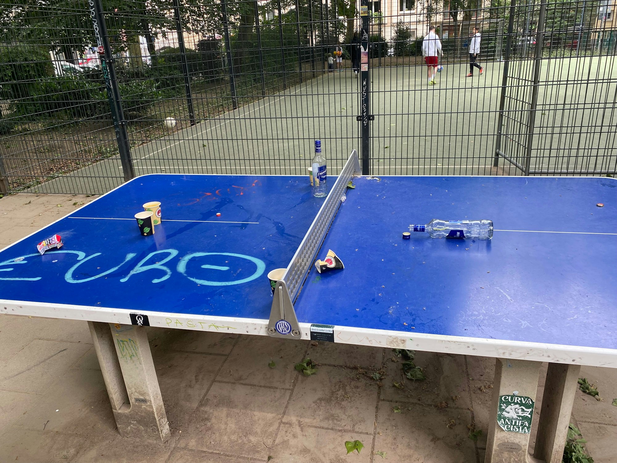 Leere Flaschen und Becher liegen auf einer Tischtennisplatte.