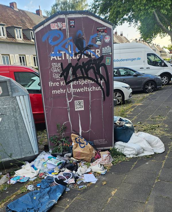 Abfall liegt neben Containern auf einem Gehweg.