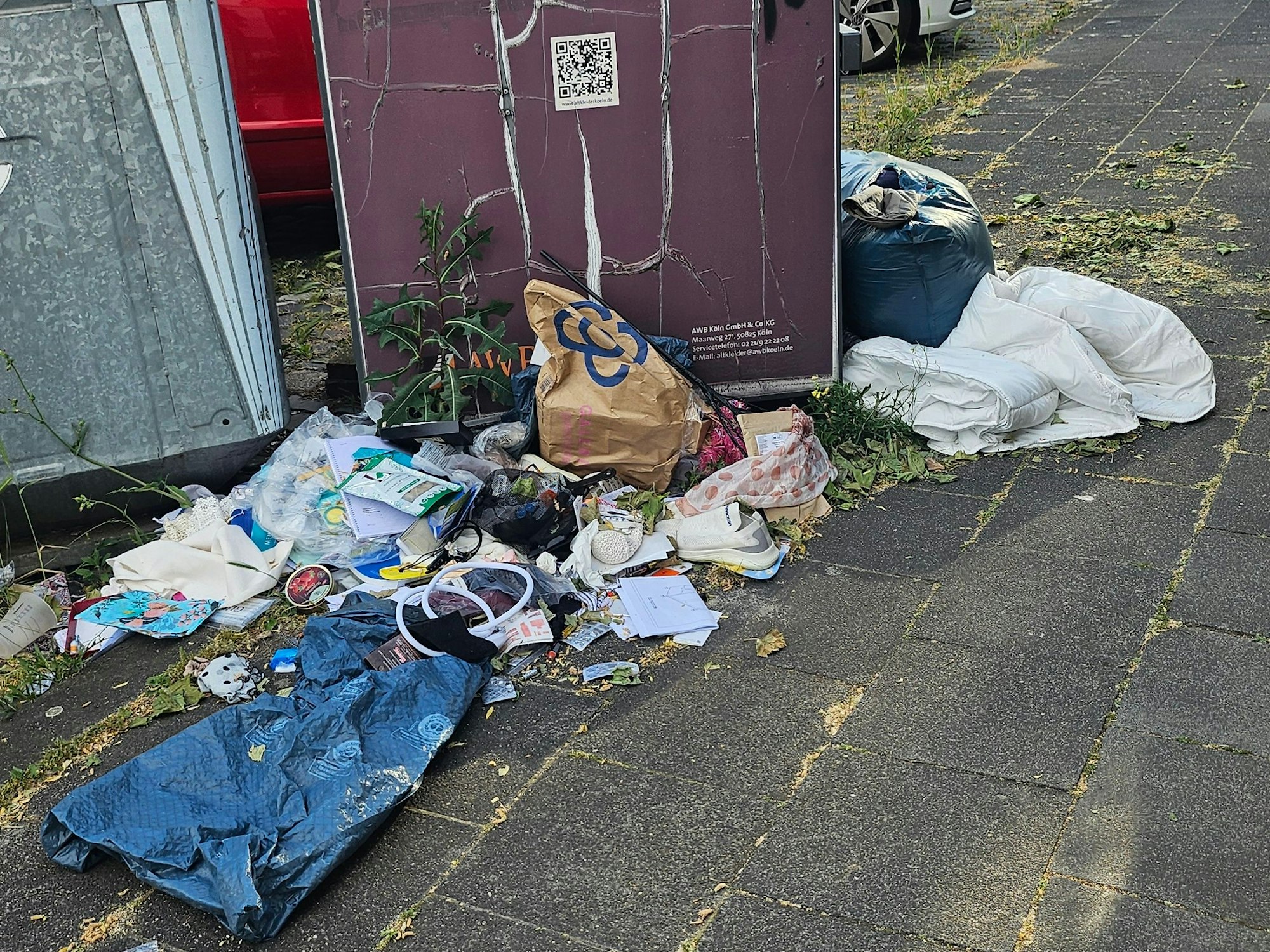Abfall liegt neben Containern auf einem Gehweg.