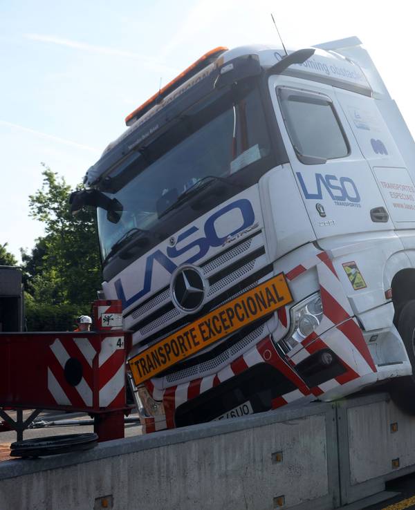 Ein Lkw hängt halb auf einer niedrigen Mauer.
