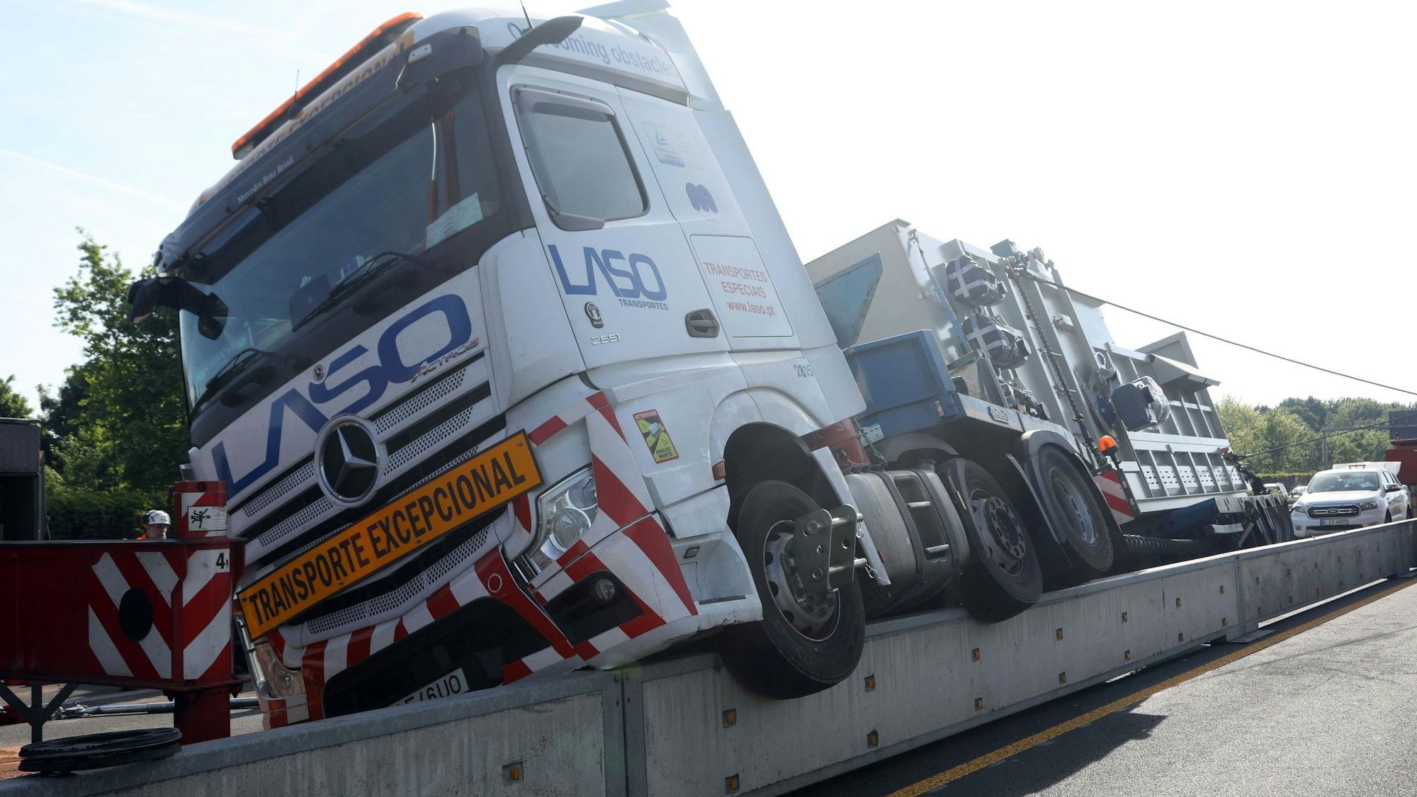 Ein Lkw hängt mit der einen Hälfte auf einer Betontrennwand.