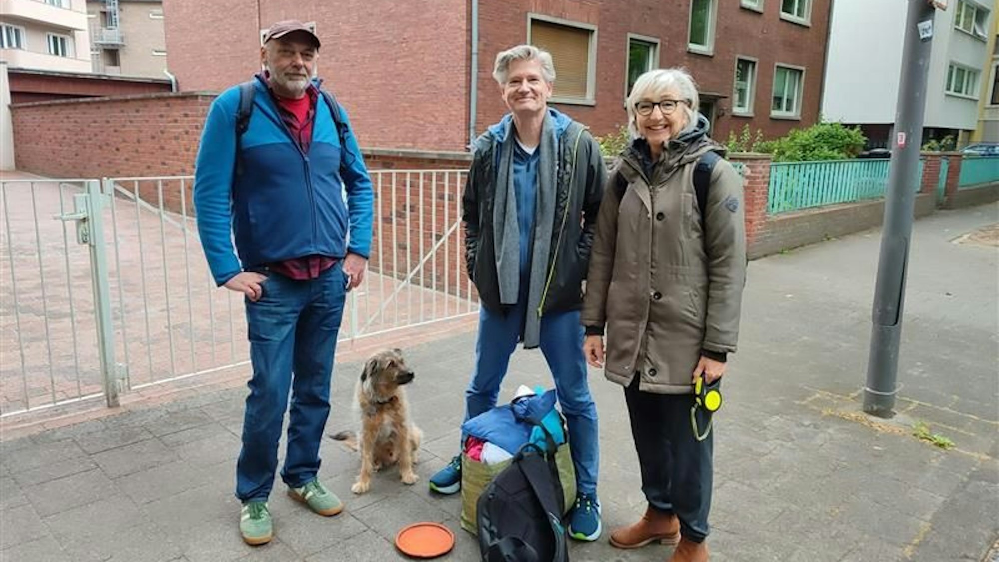 Drei Personen stehen auf dem Bürgersteig.