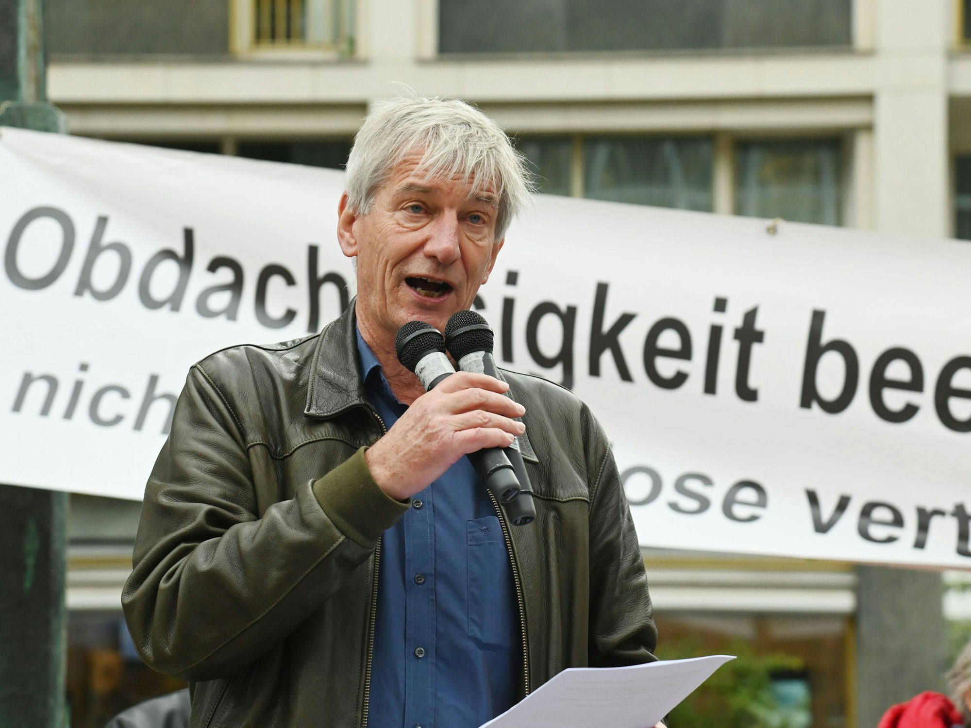 Ein Mann spricht in zwei Mikros, die er in der Hand hält.