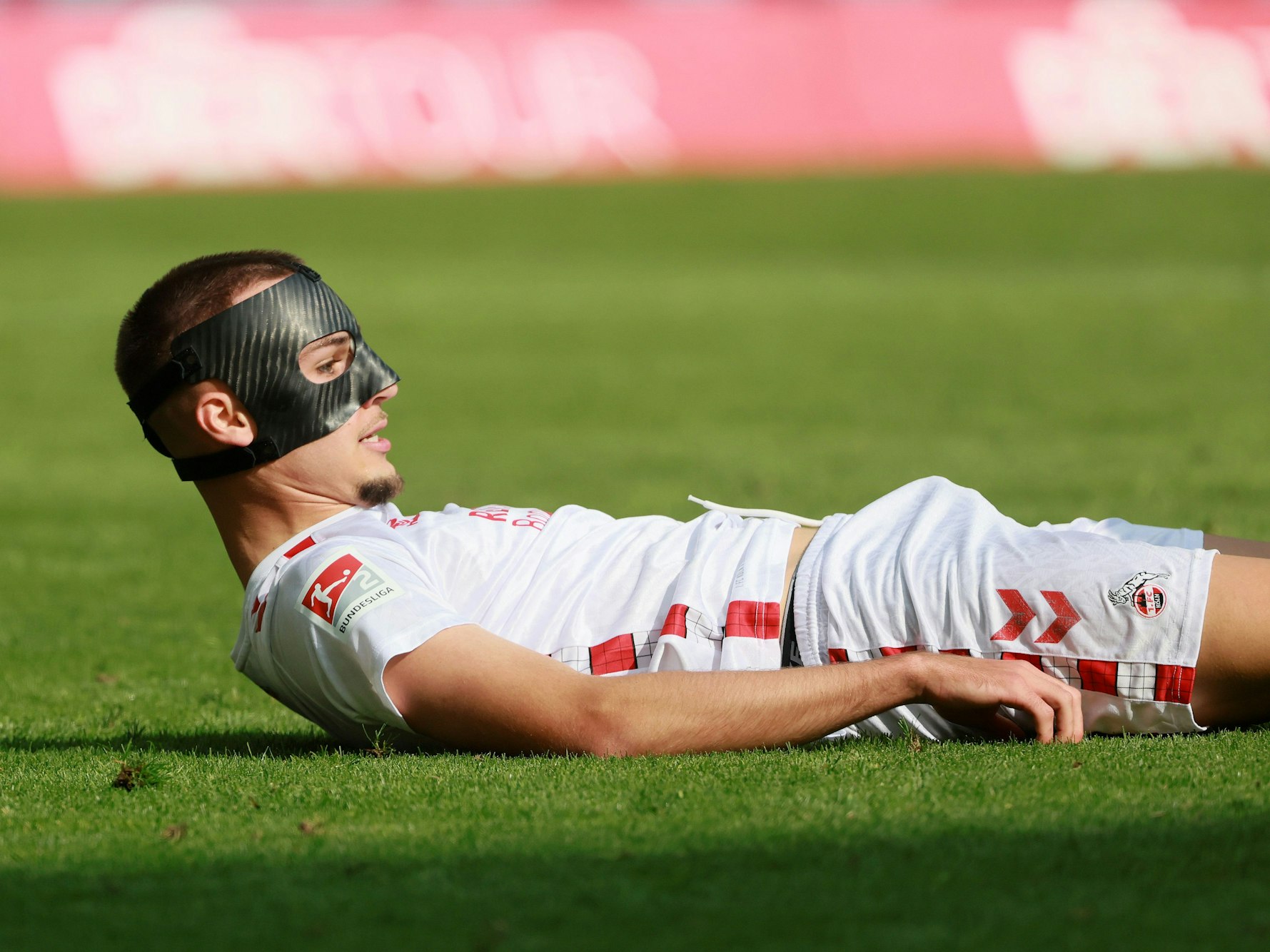 Tim Lemperle liegt mit einer schwarzen Maske im Gesicht auf dem Boden und schaut mit dem Kopf nach oben.