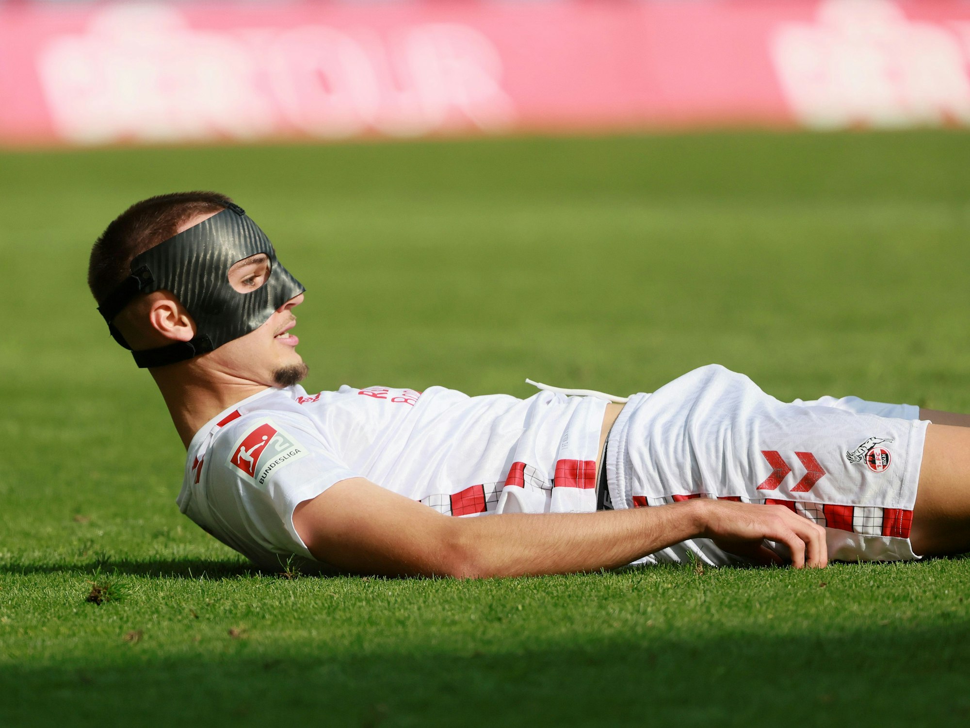 Tim Lemperle liegt mit einer schwarzen Maske im Gesicht auf dem Boden und schaut mit dem Kopf nach oben.