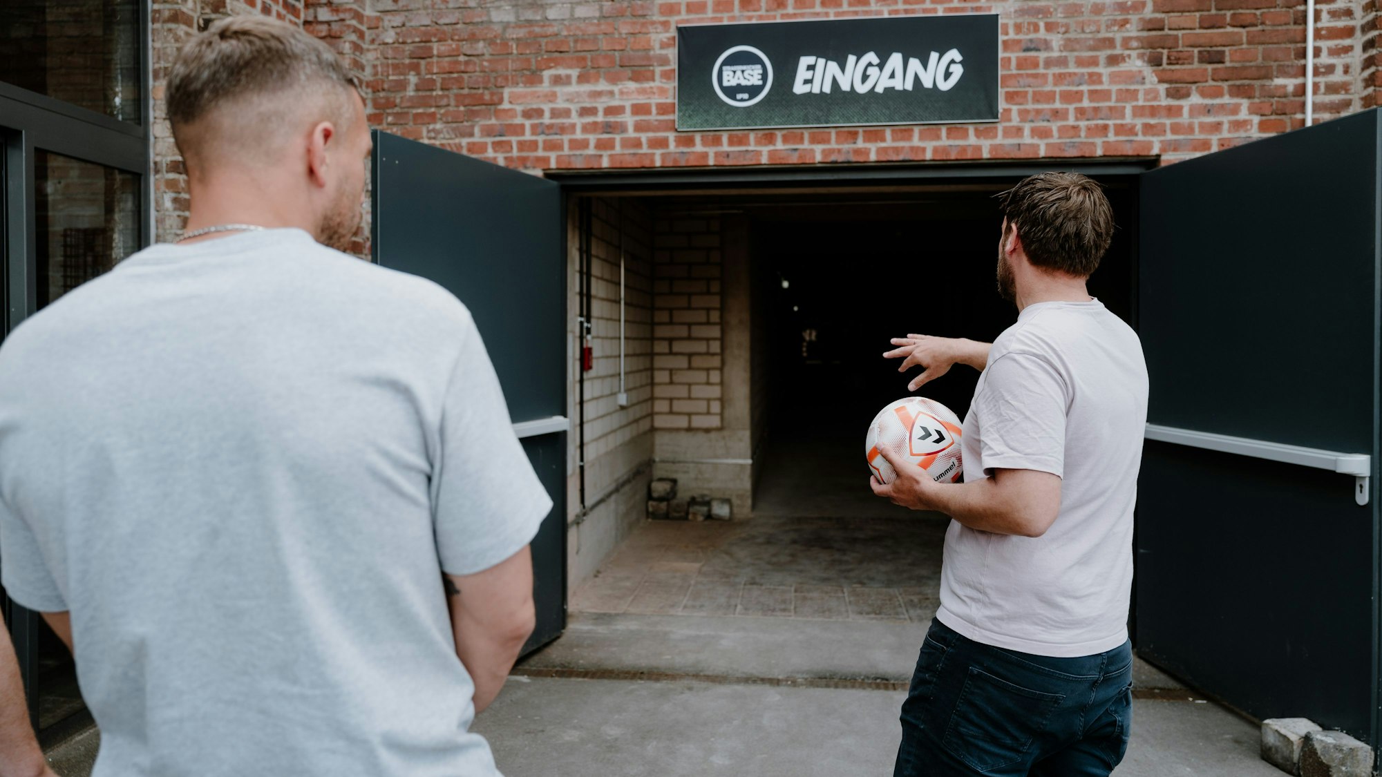Lukas Podolski mit Sebastian Lange an seiner Fußballhalle.
