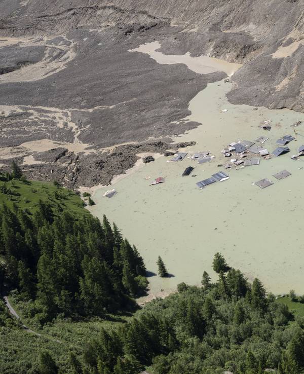 Das Wasser des Flusses Lonza fließt über Schlamm und Stein und bildet einen See, der die letzten Häuser des Dorfes Blatten in der Schweiz überflutet.