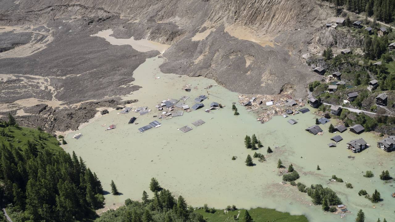 Das Wasser des Flusses Lonza fließt über Schlamm und Stein und bildet einen See, der die letzten Häuser des Dorfes Blatten in der Schweiz überflutet.