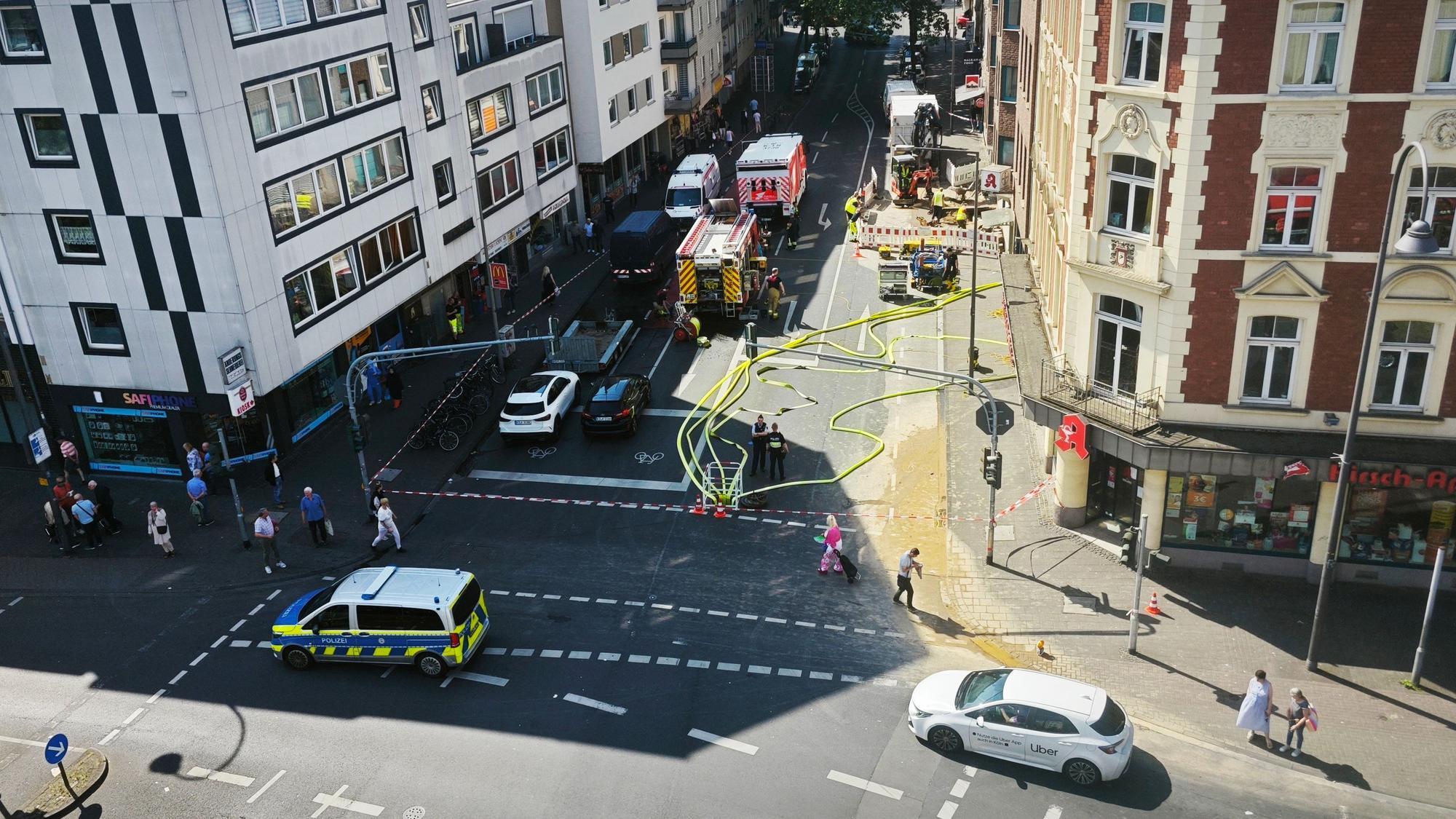 Einsatzfahrzeuge stehen auf einer Straße, auf der Fahrbahn sind mehrere Schläuche.