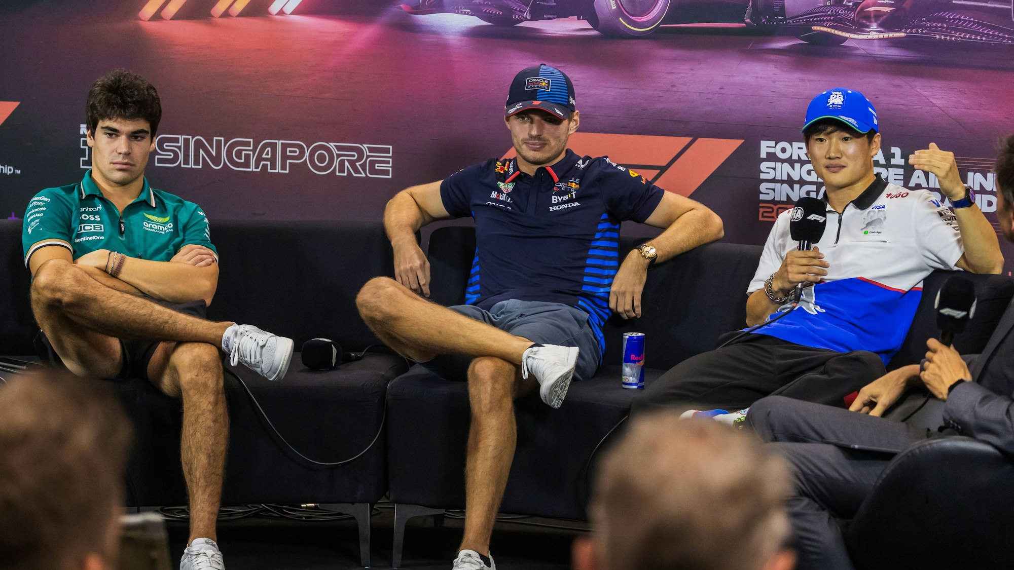 F1-Fahrer Lance Stroll (l.) am 19. September 2024 auf einer Pressekonferenz gemeinsam mit Max Verstappen und Yuki Tsunoda.