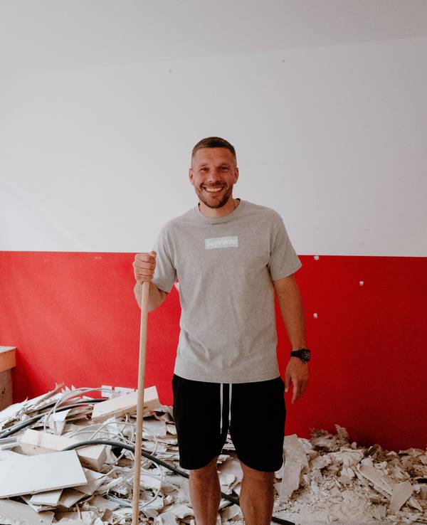 Lukas Podolski mit Besen in der Hand.
