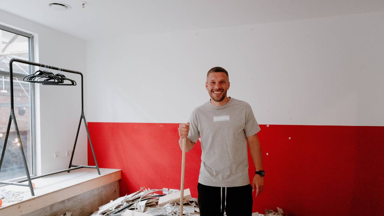Lukas Podolski mit Besen in der Hand.
