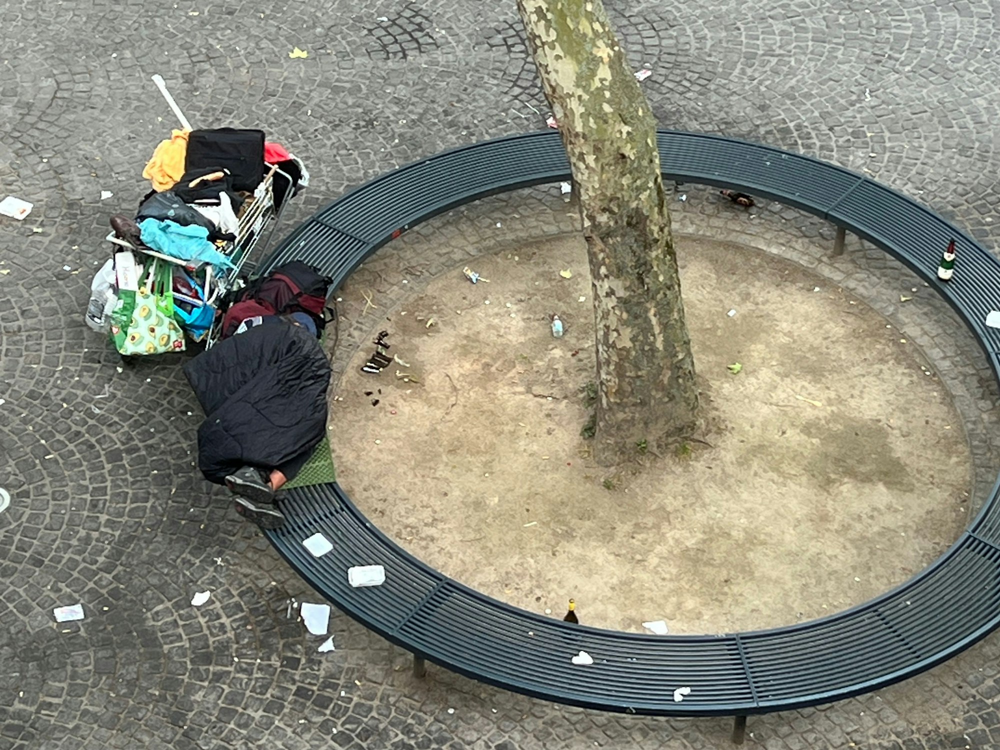 Eine Person liegt zusammengerollt auf einer Bank.