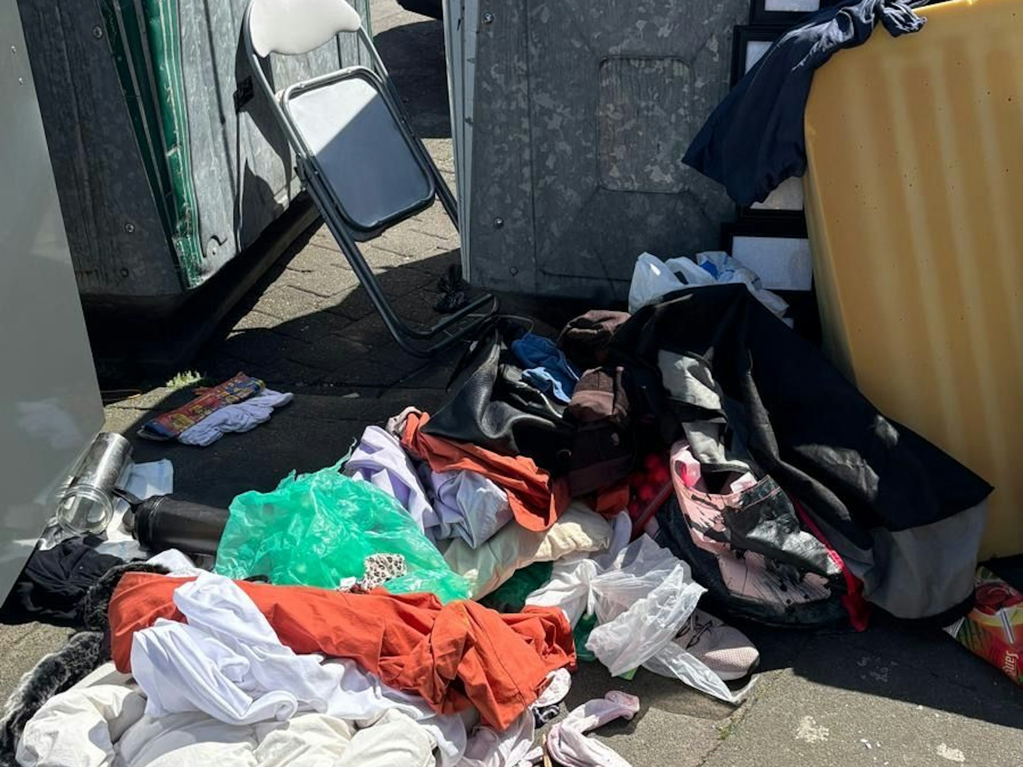 Textilen, eine Matratze und ein Klappstuhl wurden vor Containern entsorgt.