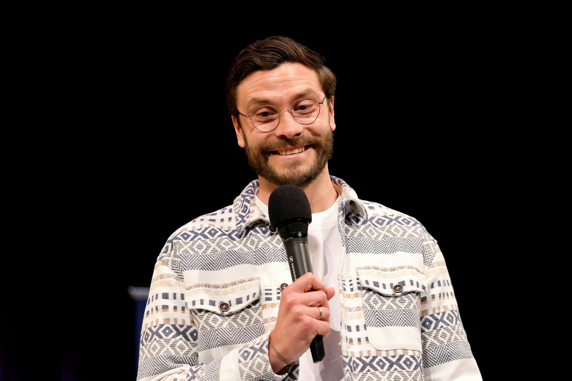 Jonas Hector spricht auf einer Bühne in ein Mikrofon.