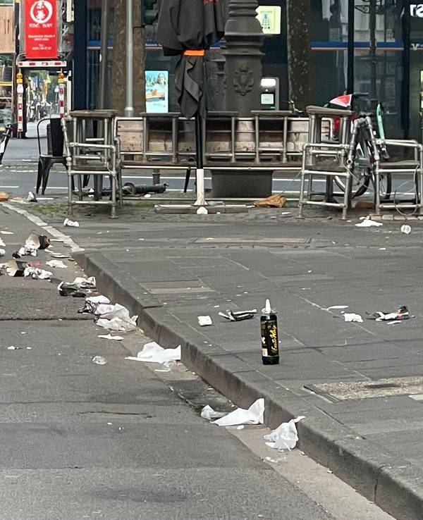 Auf einer Straße und dem Gehweg liegt Müll.