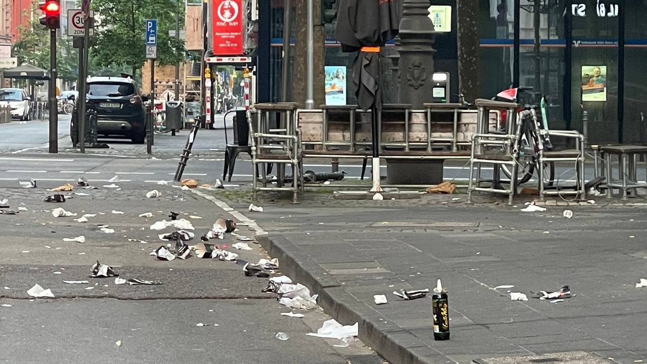 Auf einer Straße und dem Gehweg liegt Müll.