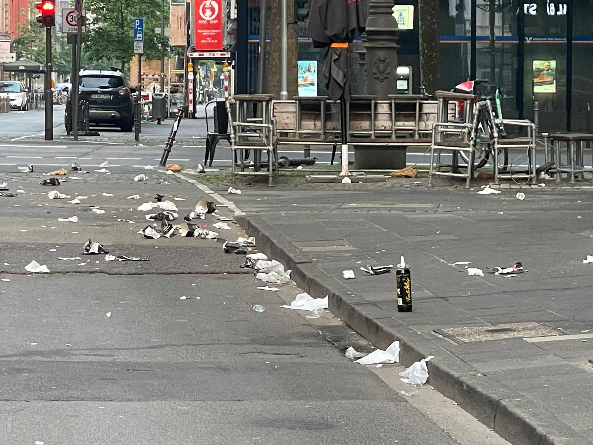 Auf einer Straße und dem Gehweg liegt Müll.