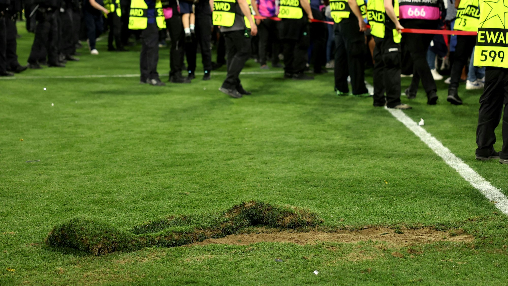 Ein großes Loch klafft nach dem Platzsturm der PSG-Fans im Rasen der Allianz-Arena. Im Hintergrund sind Ornder zu sehen.