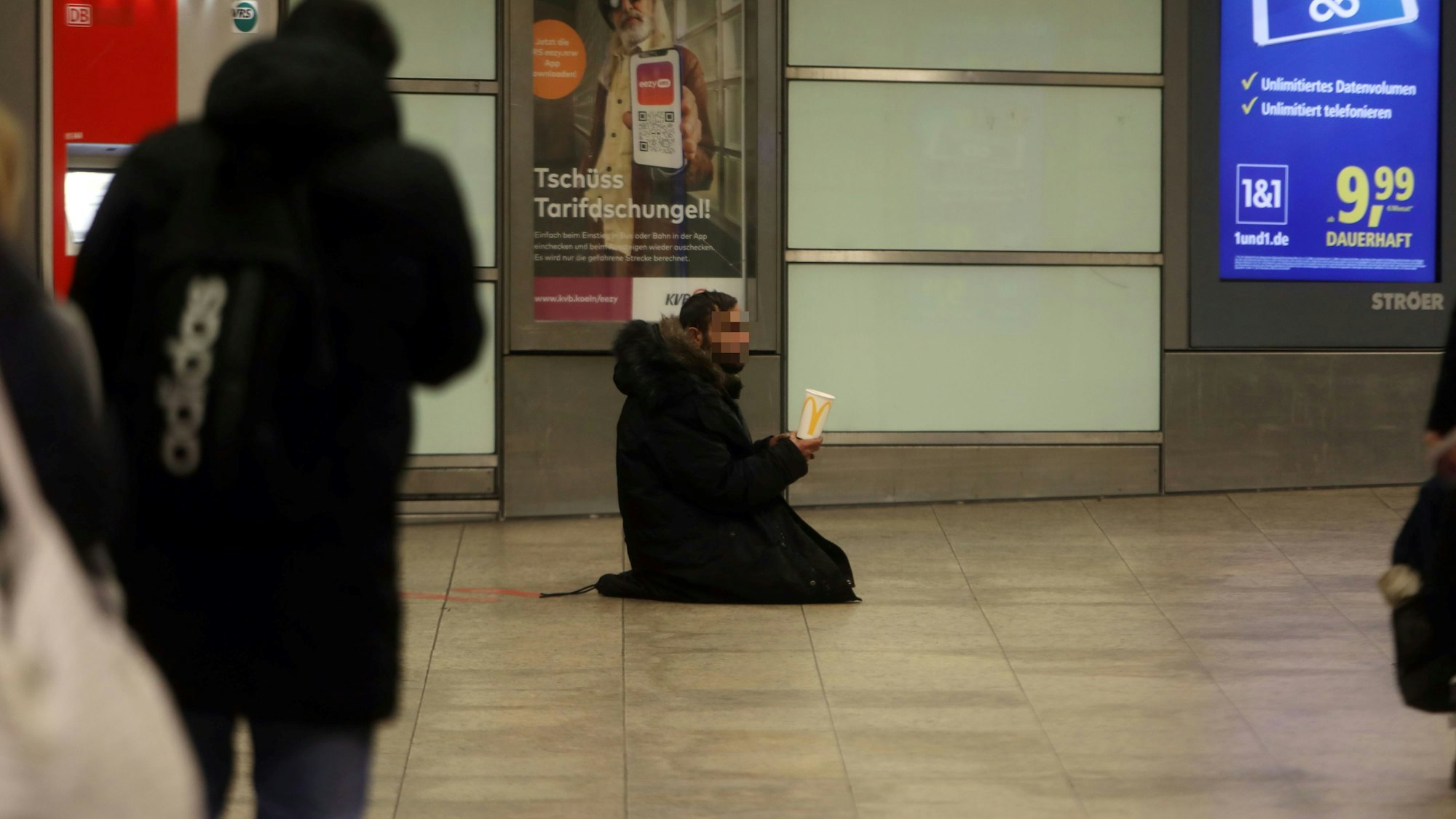 Ein Mann kniet auf dem Boden und hält einen Becher in der Hand.