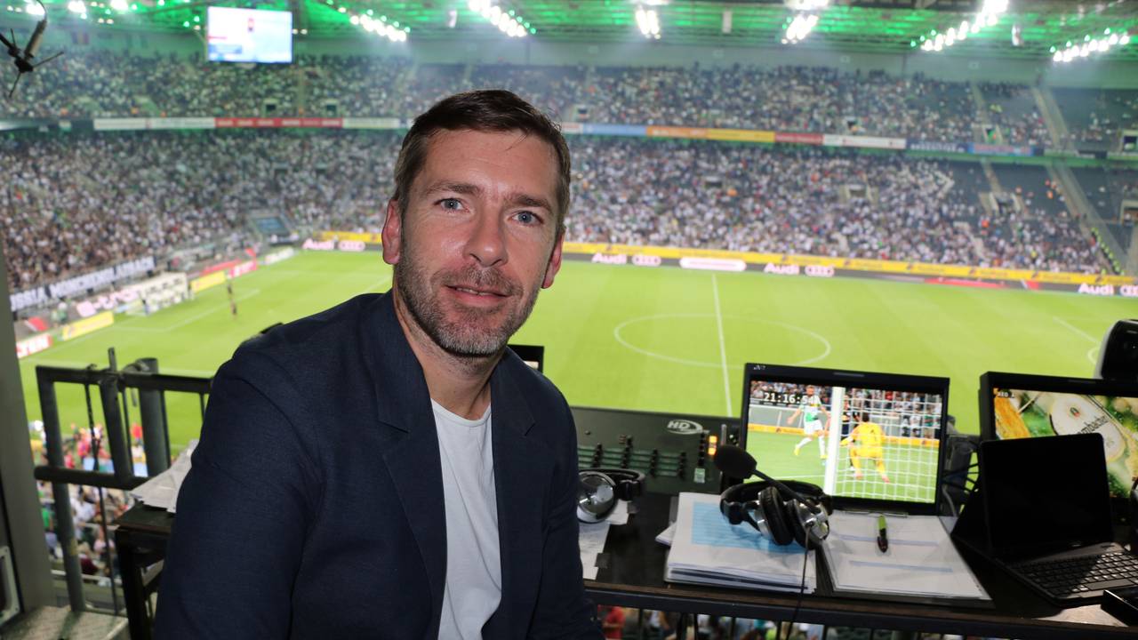 Marco Hagemann sitzt im Stadion an seinem Kommentatoren-Platz und posiert für ein Foto.