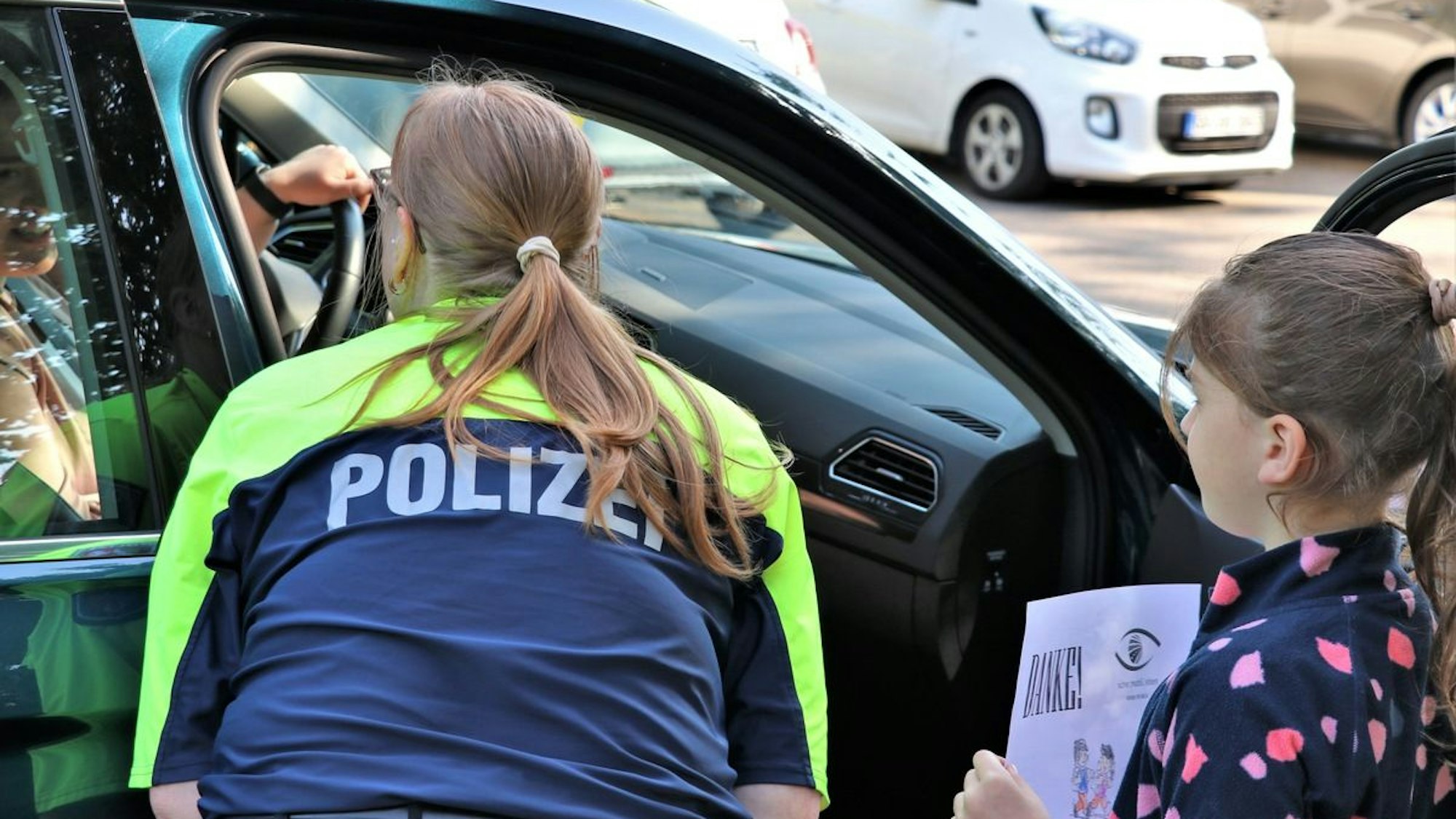 Polizeiaktion an der Christoph-Rensing-Schule in Dormagen, bei der Kinder vorbildlichen Autofahrern Dankzettel überreichten.