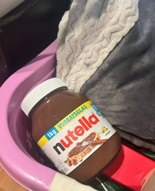 Ein großes Glas Nutella liegt in einem Korb.