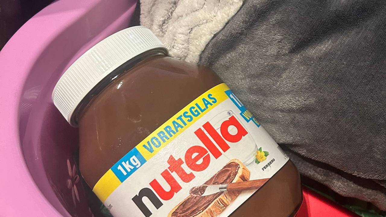 Ein großes Glas Nutella liegt in einem Korb.