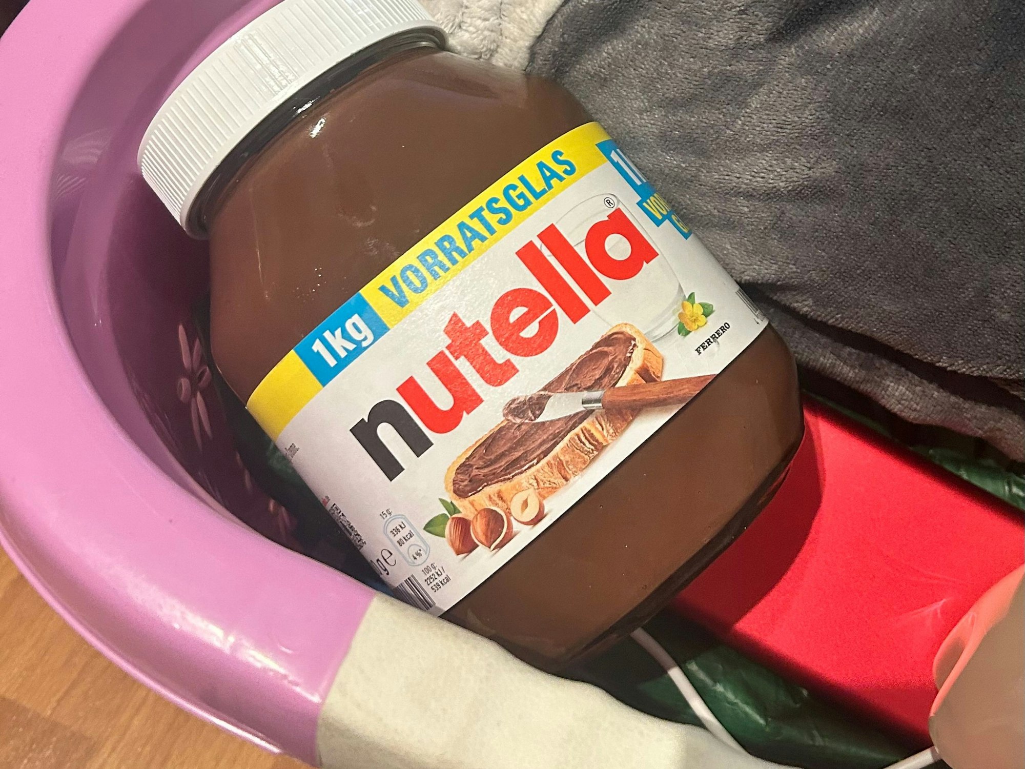 Ein großes Glas Nutella liegt in einem Korb.