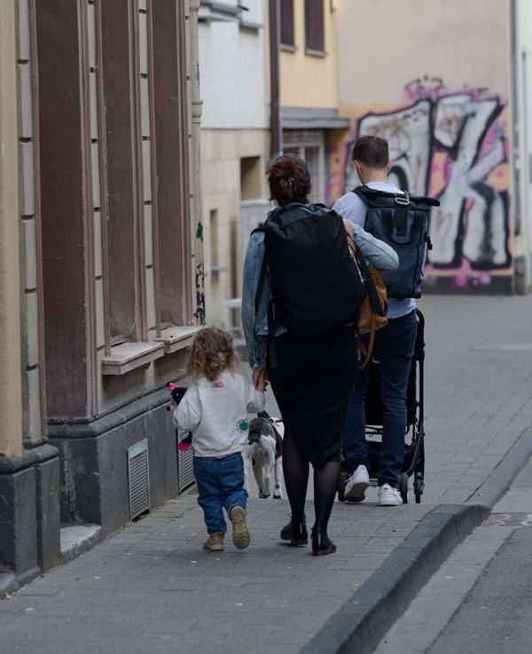 Eine Familie läuft mit Gepäck auf einer Straße.