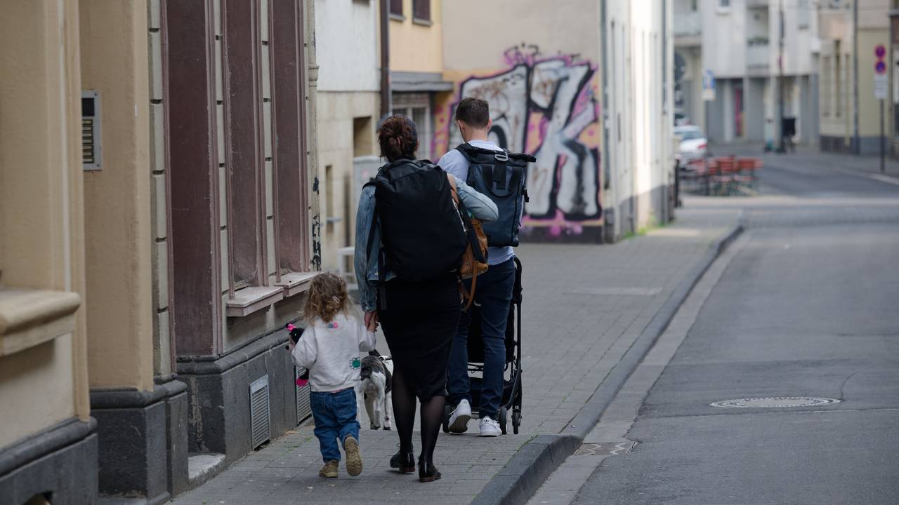 Eine Familie läuft mit Gepäck auf einer Straße.