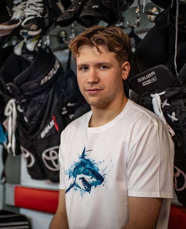 Sten Fischer sitzt im T-Shirt der Kölner Haie in der Kabine.