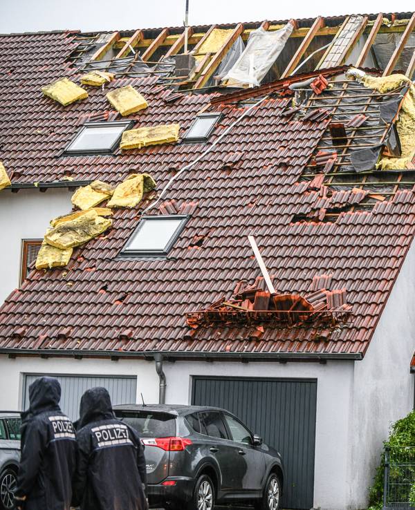 Einsatzkräfte von Feuerwehr und Polizei sind am 4. Juni im Ulmer Stadtteil Donaustetten im Einsatz, nachdem durch das Unwetter das Dach eines Reihenhauses stark beschädigt wurde.