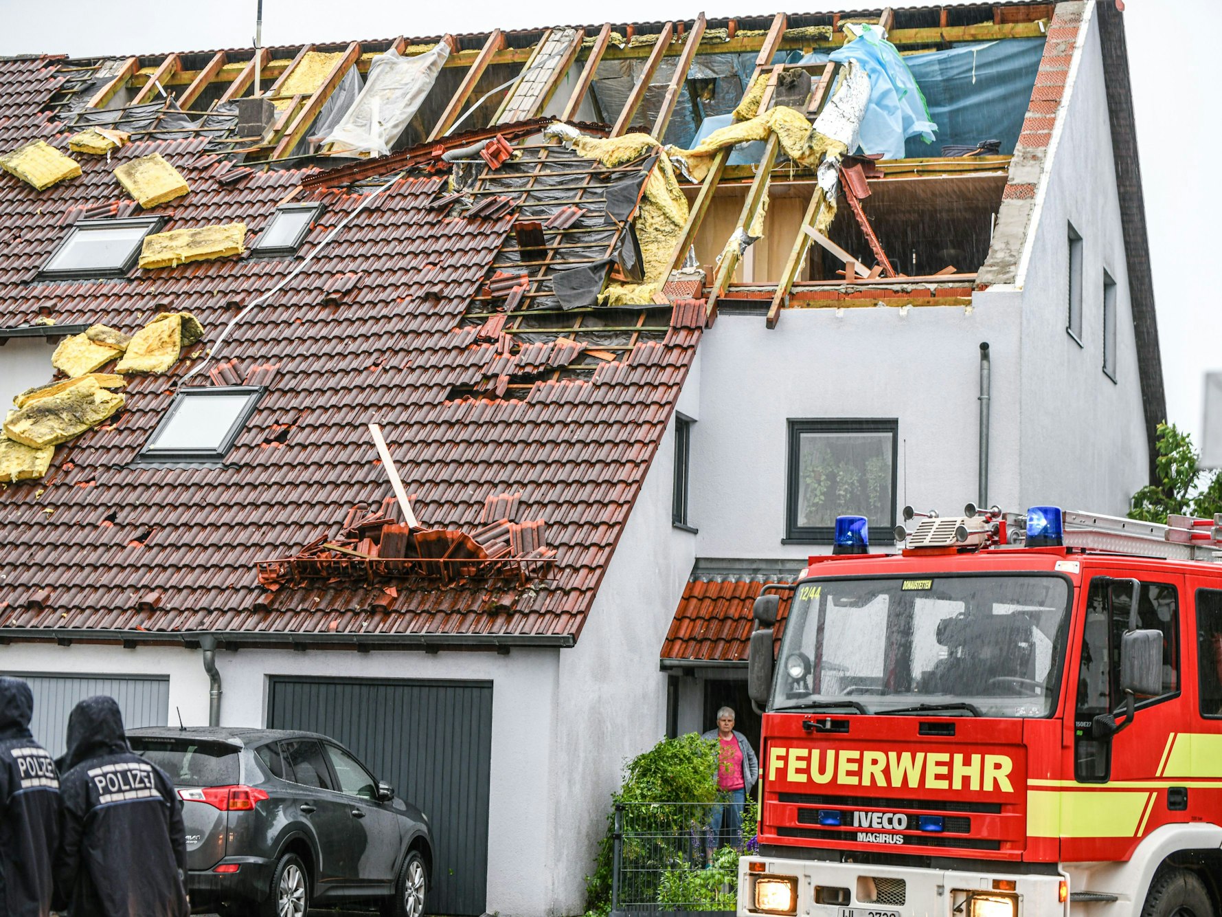 Einsatzkräfte von Feuerwehr und Polizei sind am 4. Juni im Ulmer Stadtteil Donaustetten im Einsatz, nachdem durch das Unwetter das Dach eines Reihenhauses stark beschädigt wurde.