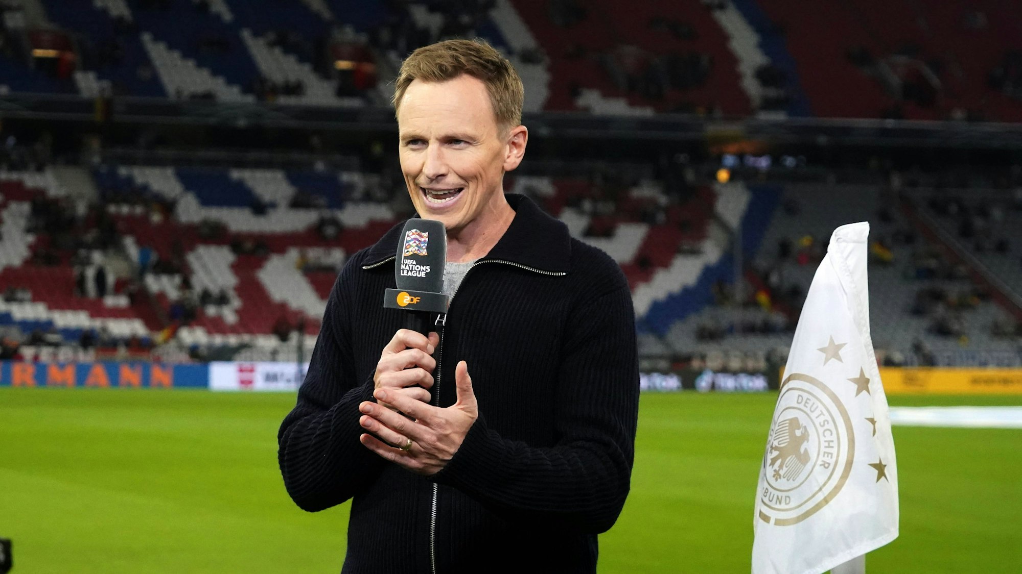 Jochen Breyer hält bei der ZDF-Übertragung zu einem Deutschland-Spiel ein Mikrofon in der Hand.