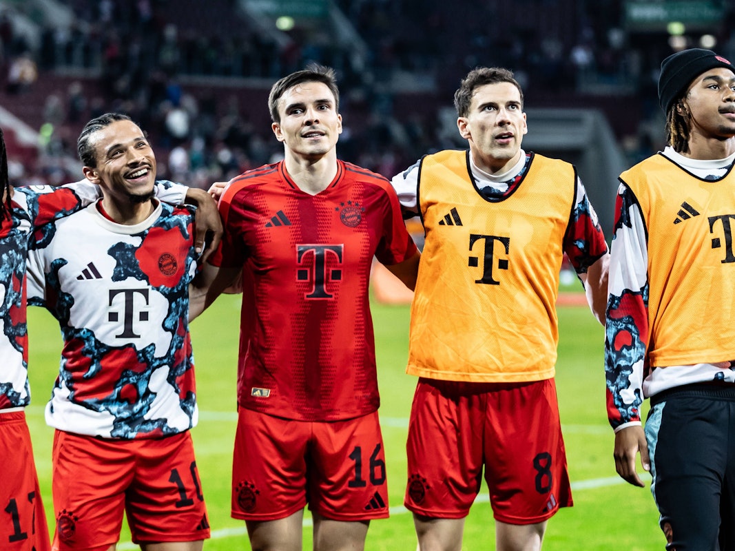 Leroy Sané, Joao Palhinha und Leon Goretzka haben sich eingehakt und feiern vor den Fans.