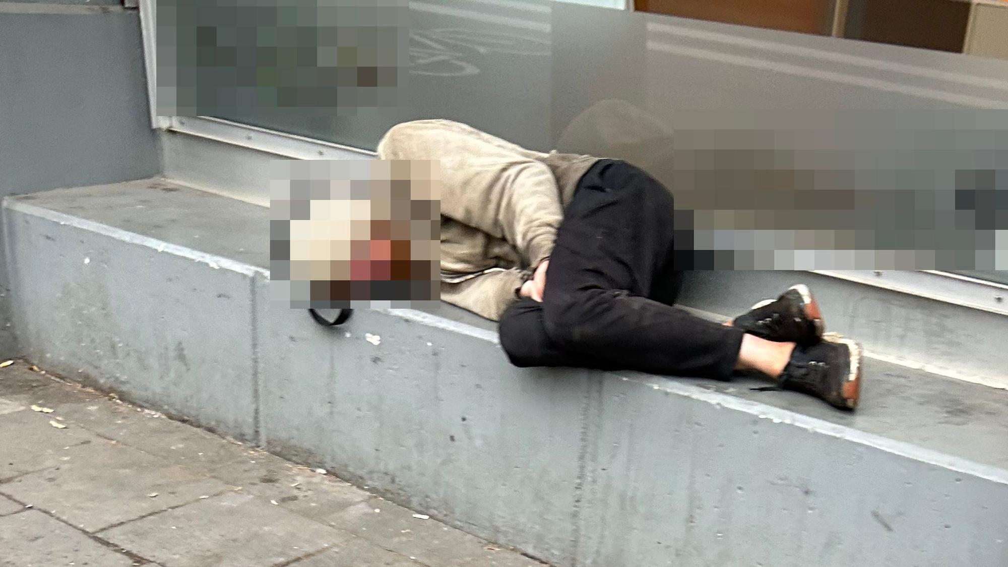 Ein Obdachloser schläft vor einem Geschäft in Köln.