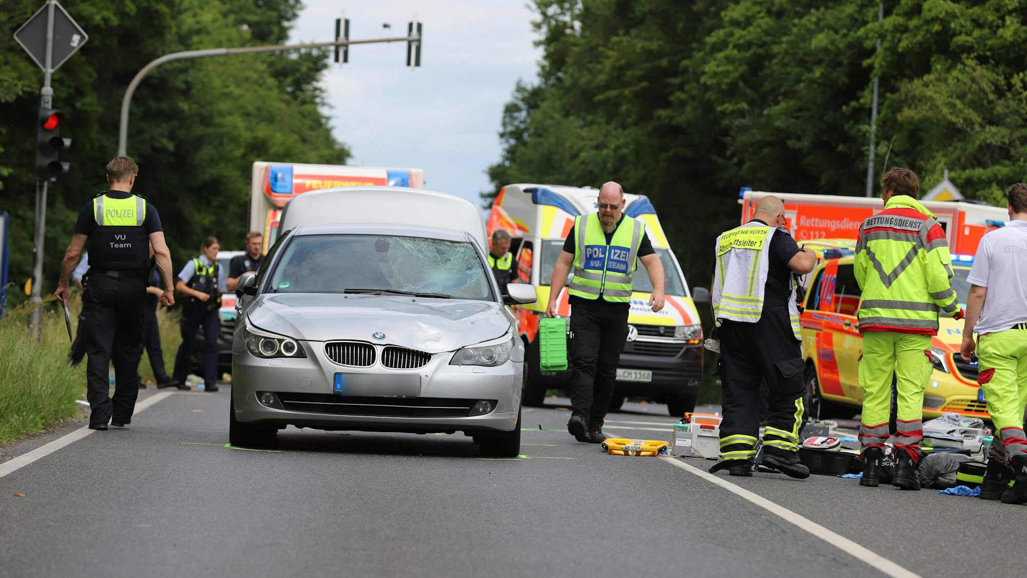 Einsatzkräfte der Polizei, der Feuerwehr und vom Rettungsdienst sind in Hürth nach einem Unfall neben dem Unfallfahrzeug im Einsatz.