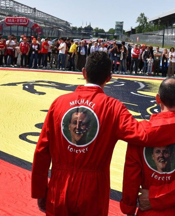 Ferrari-Besitzer erinnern in Monza mit einer Riesen-Fahne und Overalls mit der Aufschrift ‚Michael forever‘ an Rekordweltmeister Michael Schumacher.