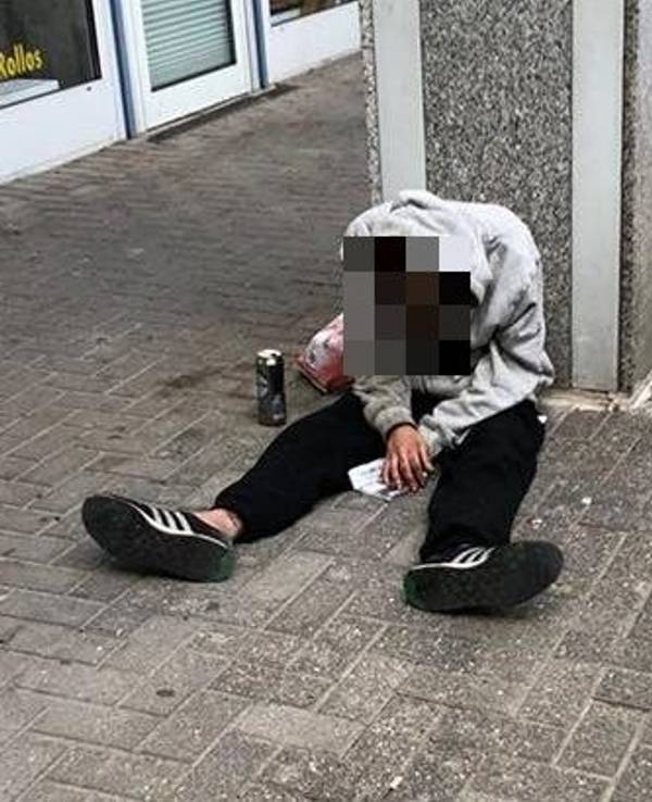 Ein Mann sitzt auf dem Boden, sein Oberkörper ist nach vorne gekippt.