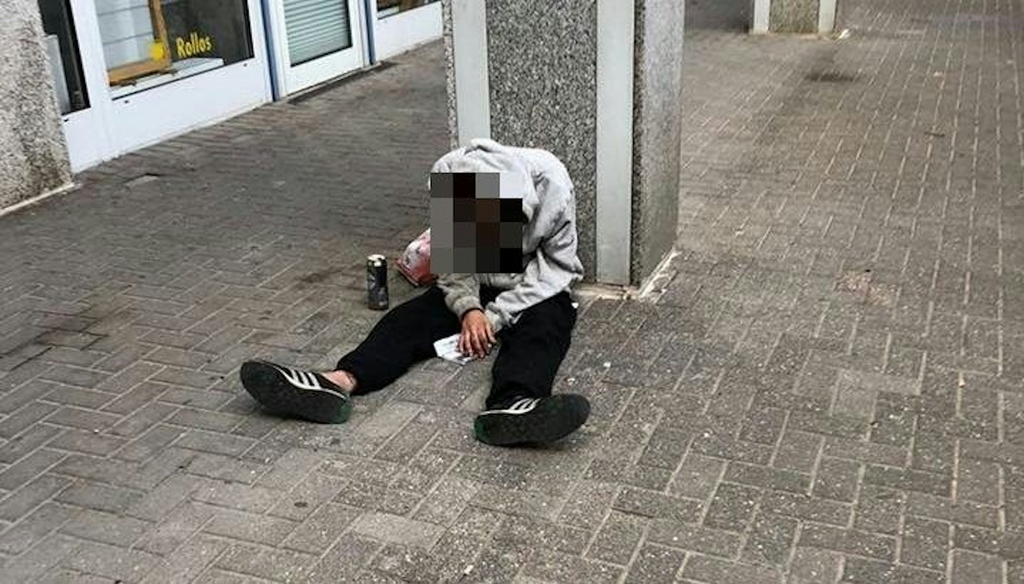 Ein Mann sitzt auf dem Boden, sein Oberkörper ist nach vorne gekippt.