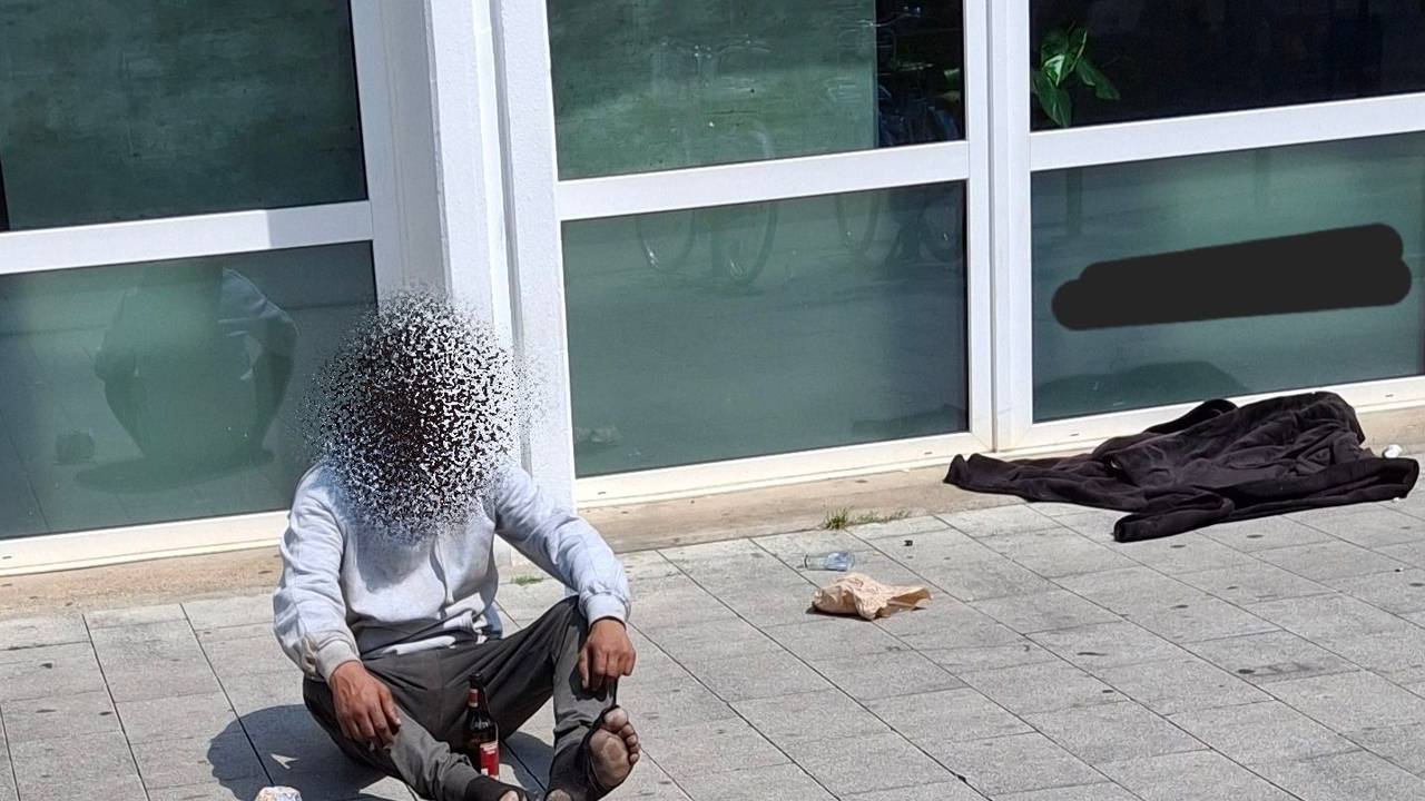 Ein Mann sitzt auf dem Boden, er trägt kaputte Socken.
