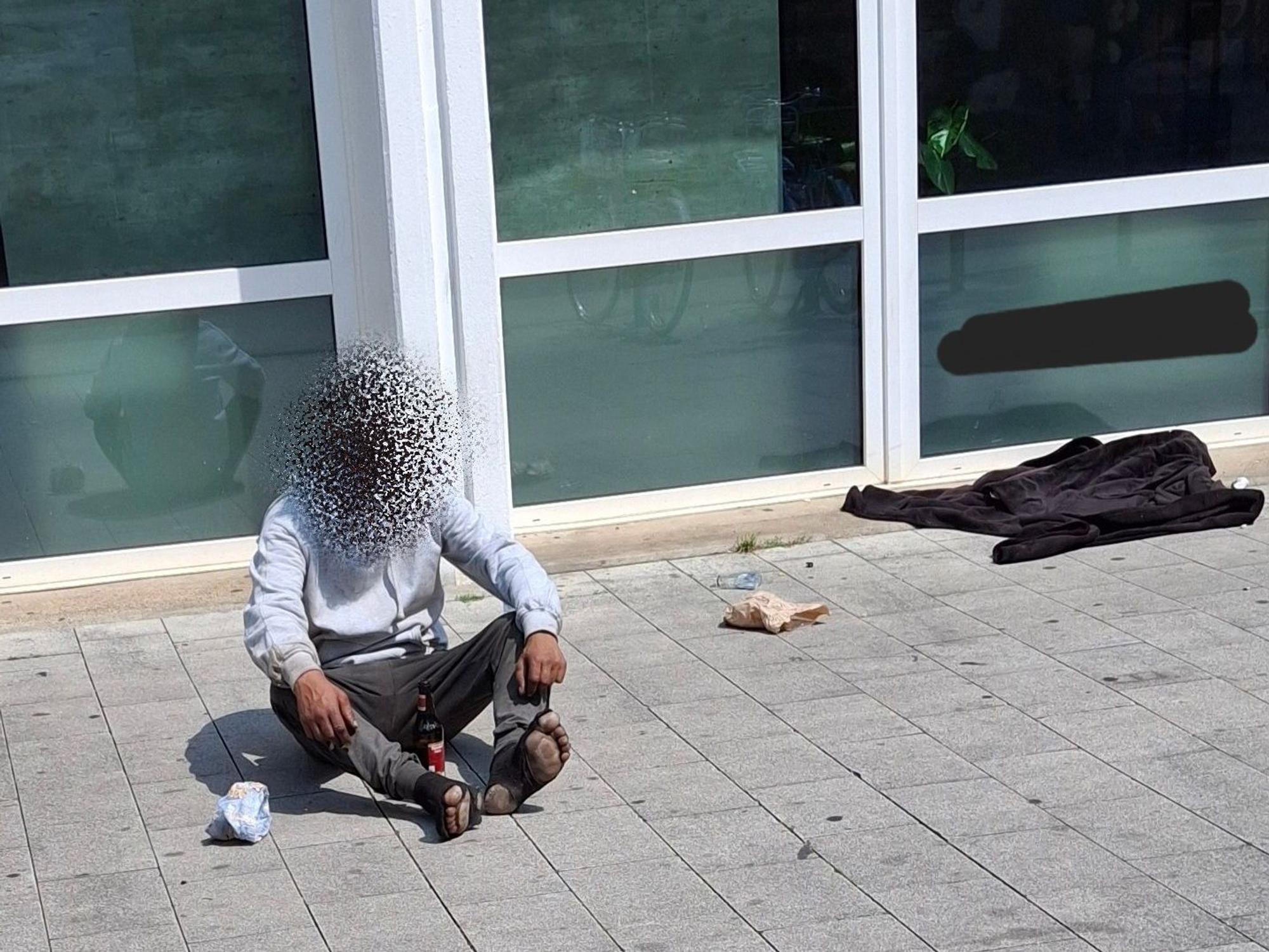 Ein Mann sitzt auf dem Boden, er trägt kaputte Socken.