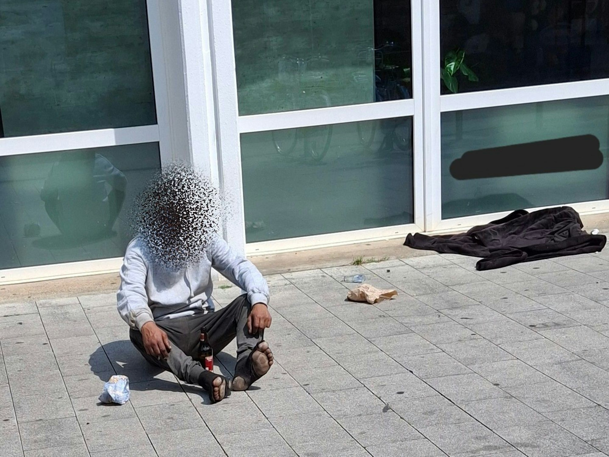 Ein Mann sitzt auf dem Boden, er trägt kaputte Socken.