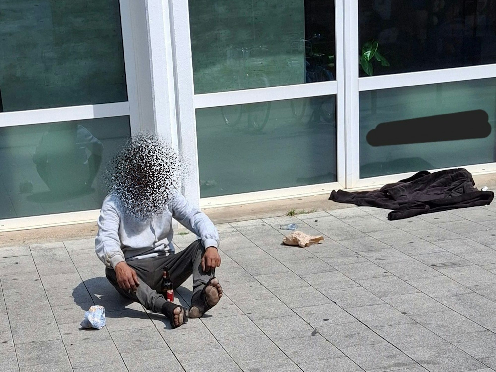 Ein Mann sitzt auf dem Boden, er trägt kaputte Socken.