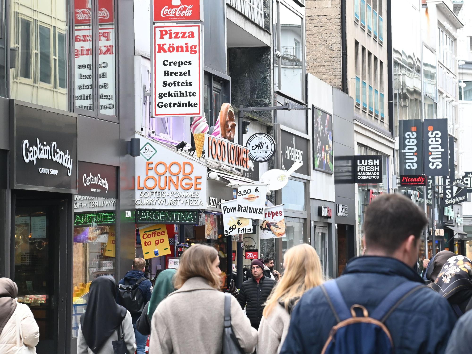 Menschen laufen durch eine Einkaufsstraße.
