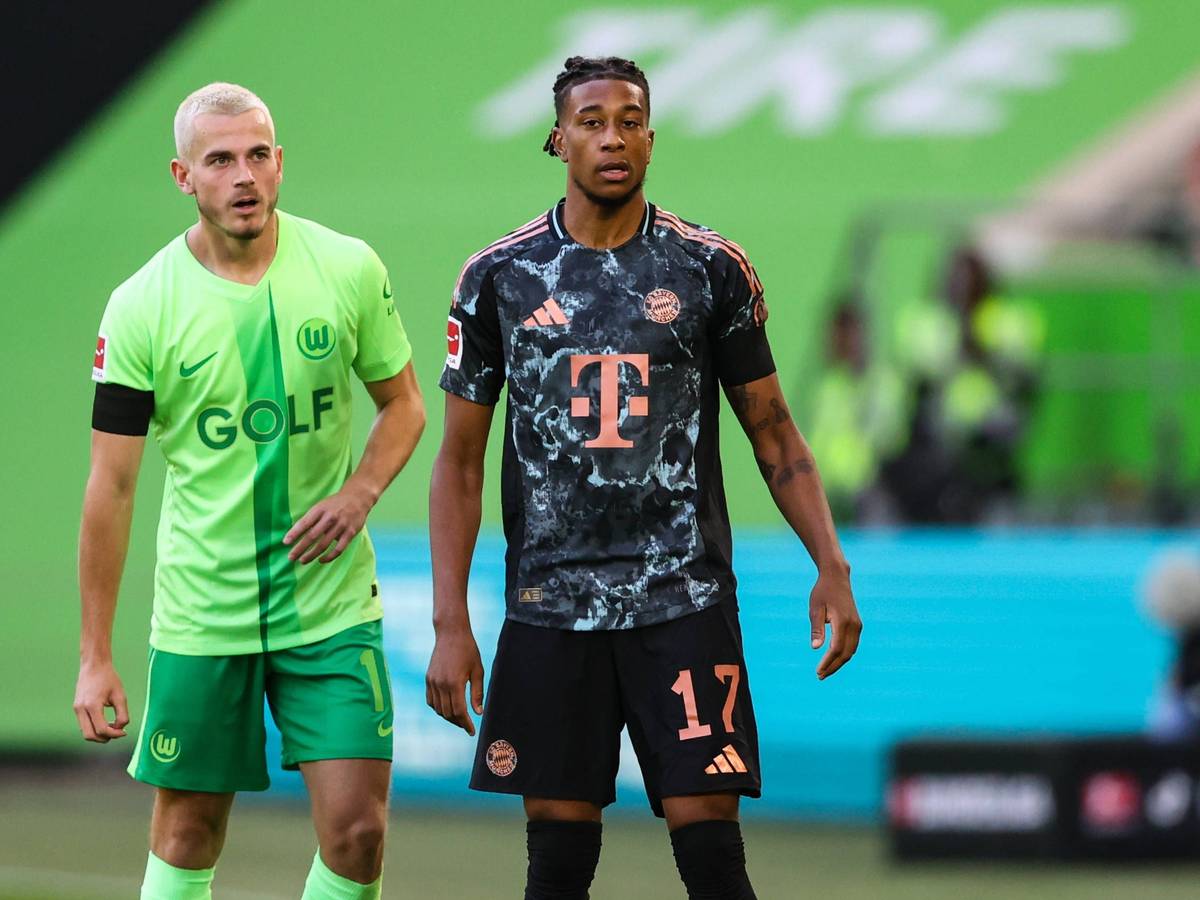 Jakub Kaminski und Michael Olise stehen beim Spiel des VfL Wolfsburg gegen den FC Bayern nebeneinander auf dem Platz.